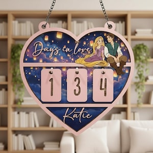 May include: A heart-shaped wooden sign with the text "Days in love" and the numbers "134". The sign features a cartoon couple and the name "Katie". The background shows a night sky with floating lanterns.
