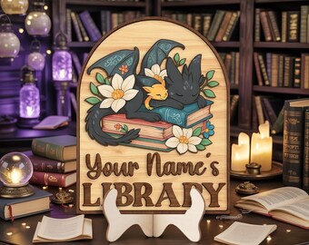 May include: Wooden sign with a dragon and kitten design, resting on books, with the text "Your Name's LIBRARY". The sign is supported by a white stand, with a library background.