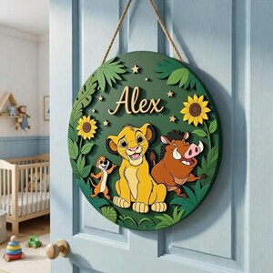 May include: A round, green wooden sign featuring characters from The Lion King. The sign includes the name "Alex" in a cursive font, sunflowers, and jungle foliage. The sign is hanging on a light blue door.