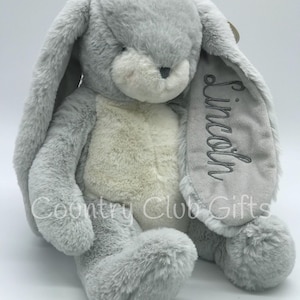 May include: A plush gray bunny rabbit with long floppy ears and a cream-colored belly. The name "Lincoln" is embroidered on one ear. The text "Country Club Gifts" is printed on the bunny.
