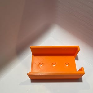 May include: Orange 3D printed plastic case with three holes.