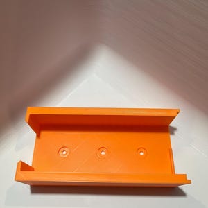 May include: Orange plastic 3D printed wall mount with three holes.