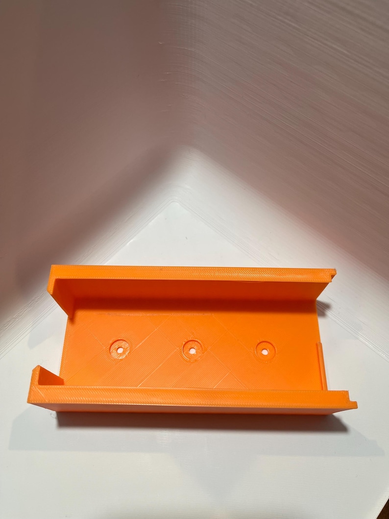 May include: Orange plastic 3D printed wall mount with three holes.