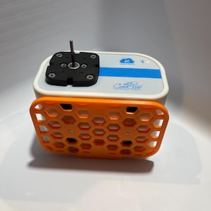 May include: A white and blue rectangular device with a black top and an orange honeycomb-patterned cover. The device has the text "Coral Vue" and a Bluetooth symbol. The black top has a metal rod and screws.