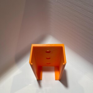 May include: Orange plastic wall mount with three holes.