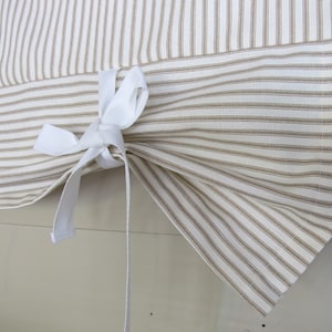 May include: A white valance with brown stripes and a white ribbon tie. The valance is made of a lightweight fabric and has a simple, elegant design.