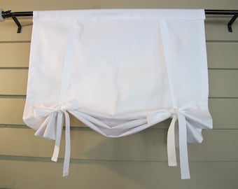 May include: White cotton cafe curtain with two tie-backs on each side. The curtain is hung on a black rod with white finials.