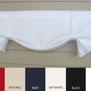 May include: White valance with a curved bottom edge. The valance is hung on a black curtain rod. The valance is available in a variety of colors, including red, natural, navy, off white, black, and white.