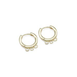 May include: Gold hoop earrings with three small jump rings hanging from the bottom.