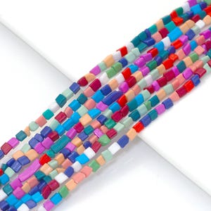 Può includere: Un filo di perline quadrate colorate. Le perline sono in varie tonalità di blu, verde, rosa, rosso e bianco.