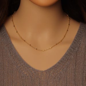 May include: A delicate gold chain necklace with small round beads.