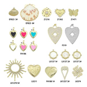 May include: A collection of gold-colored pendants and charms in various shapes, including a seashell, hearts, a butterfly, and a sunburst design. Some charms feature colorful enamel or gemstone accents. The image includes product codes.
