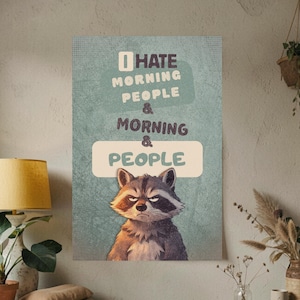 Puede incluir: Un póster con una ilustración de mapache y el texto "I HATE MORNING PEOPLE & MORNING & PEOPLE" en un esquema de color verde azulado y beige. El mapache tiene una expresión severa. El póster se muestra en un salón.