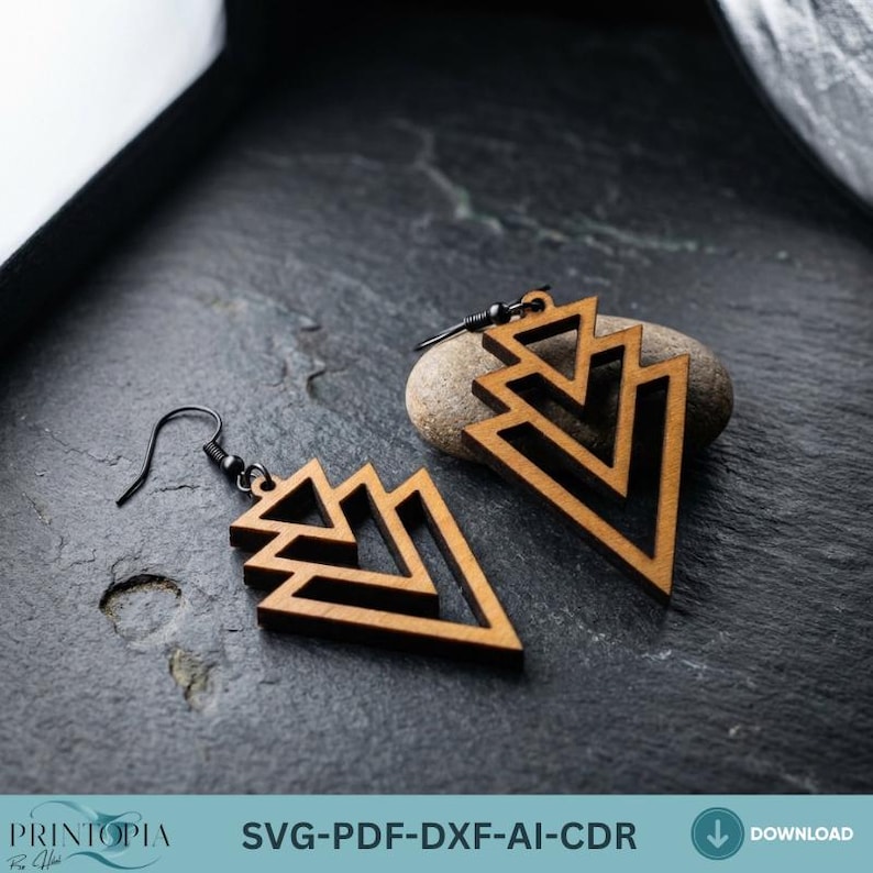 May include: Wooden geometric earrings with a layered triangle design. The earrings are a light brown color with black metal hooks. The earrings are displayed on a dark gray stone surface. The image also includes the text "SVG-PDF-DXF-AI-CDR".
