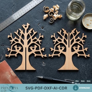May include: Two wooden tree cutouts with bird designs. The trees are light brown and have intricate branch and bird details. The image also includes a ruler, wood shavings, a jar, and the text "SVG-PDF-DXF-AI-CDR".