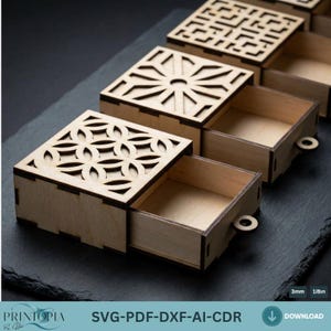 May include: A set of square wooden boxes with decorative laser-cut lids. The boxes are open, showing the inside, and have small circular handles. The text "SVG-PDF-DXF-AI-CDR" is visible.