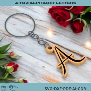 May include: Wooden keyring with the letter "A" in a decorative font, outlined in black. The keyring is attached to a silver metal ring and chain. The text "A TO Z ALPHABET LETTERS" is at the top. Roses are in the background.