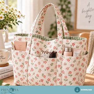 May include: A cream-colored fabric tote bag featuring a repeating pattern of small pink flowers and green leaves. The bag has two sturdy handles, an open top, and multiple exterior pockets containing a notebook, a pen, and a small bottle.