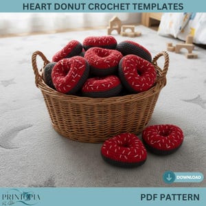Könnte beinhalten: Ein Weidenkorb voller herzförmiger Häkel-Donuts. Die Donuts sind rot mit weißen Nähten und grauen Böden. Der Text "HEART DONUT CROCHET TEMPLATES" steht oben. Die Wörter "PDF PATTERN" und ein Download-Symbol stehen unten.
