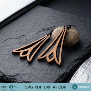 May include: A pair of wooden earrings with a geometric design. The earrings are a light brown color and have a triangular shape with a decorative cutout at the bottom. The earrings are displayed on a dark gray surface.