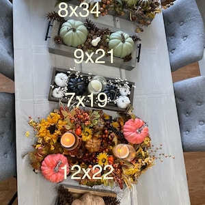 Puede incluir: Una colecci&oacute;n de bandejas y centros de mesa decorativos con tem&aacute;tica oto&ntilde;al. La imagen muestra varios arreglos con calabazas, girasoles, velas y follaje de oto&ntilde;o. Los tama&ntilde;os son 20x86 cm, 23x53 cm, 18x48 cm, 30x56 cm y 23x30 cm.