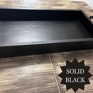 Puede incluir: Una bandeja rectangular de madera negra maciza con un perfil bajo. La bandeja tiene un acabado liso y mate y est&aacute; colocada sobre una superficie de madera. El texto "SOLID BLACK" se muestra en forma de estrella negra.