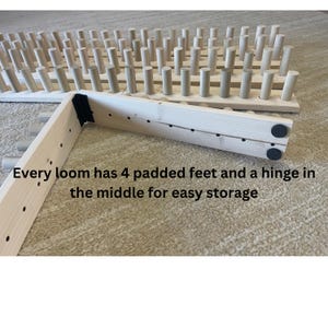 May include: Wooden weaving loom with numerous pegs, featuring a hinged design for compact storage. The text reads: "Every loom has 4 padded feet and a hinge in the middle for easy storage."