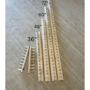 May include: Five wooden dowel rods with varying lengths of 36 inches, 48 inches, 60 inches, and 72 inches. Each rod has evenly spaced wooden dowels protruding from the side. A smaller wooden dowel rod with a folding design is also included.