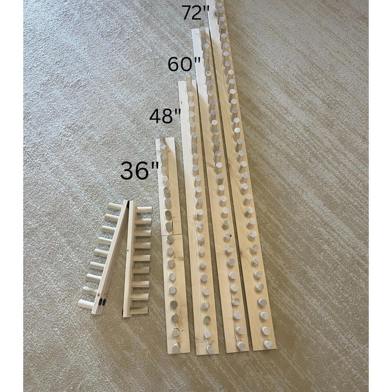 May include: Wooden peg boards in various lengths: 36 inches, 48 inches, 60 inches, and 72 inches. The boards are made of light-colored wood and feature evenly spaced wooden pegs. The boards are designed for organizing and displaying items.