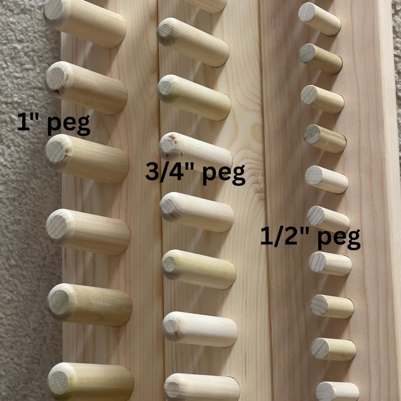 May include: Wooden pegboard with various sizes of wooden pegs. The pegs are labeled as 1", 3/4", and 1/2" in size. The pegs are cylindrical and made of light-colored wood, mounted on a wooden board.