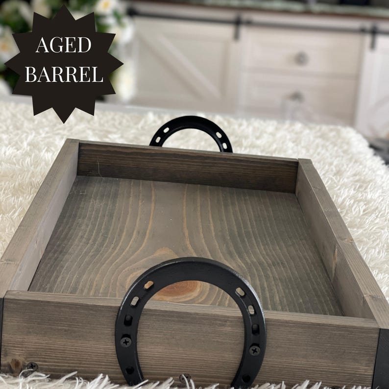 Puede incluir: Bandeja de madera Aged Barrel con tinte gris oscuro y asas de herradura negras. La bandeja tiene forma rectangular y est&aacute; hecha de madera. El texto "AGED BARREL" est&aacute; en forma de estrella negra en la esquina superior izquierda.