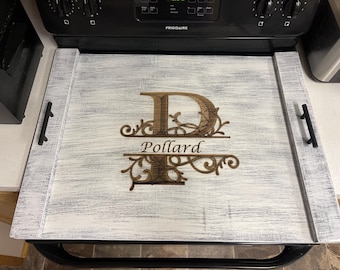 May include: White wooden serving tray with a black metal frame and handles. The tray has a distressed finish and features a laser-cut design of the letter "P" with a decorative flourish and the name "Pollard" underneath.