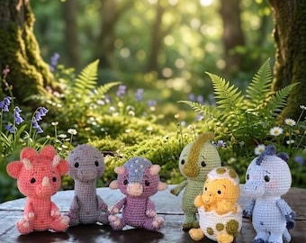 May include: A collection of six small crocheted dinosaur figures in various colors including pink, grey, purple, green, and blue, with one yellow dinosaur emerging from a white and green speckled egg, all arranged on a dark wooden surface.