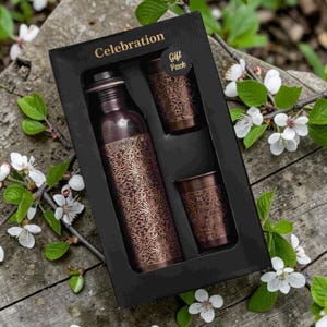 May include: A copper-colored metal water bottle and two matching tumblers with an intricate embossed floral pattern, presented in a black rectangular gift box labeled Celebration and Gift Pack in gold text on the interior packaging surface.