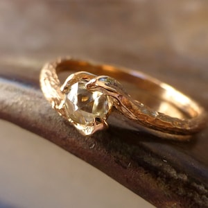 May include: A gold ring with a textured band and a round, clear gemstone set in the center.