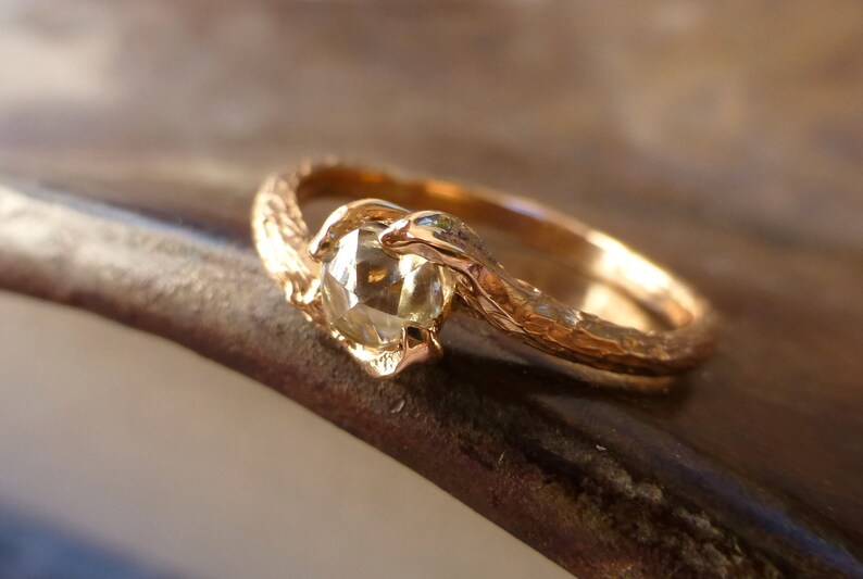 May include: A gold ring with a textured band and a round, clear gemstone set in the center.