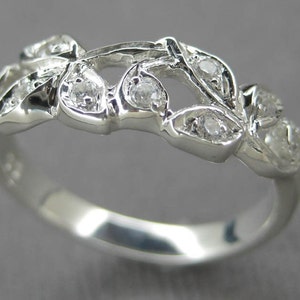 Puede incluir: Un anillo de plata con un delicado dise&ntilde;o de hojas y peque&ntilde;as piedras transparentes.