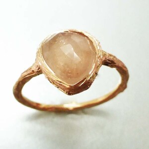 May include: A gold ring with a unique, textured band and a large, clear, faceted gemstone.