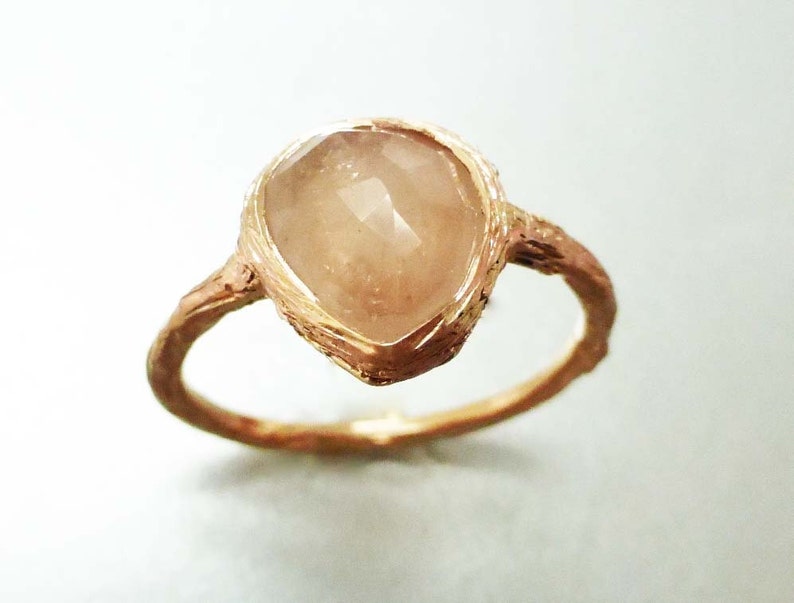 May include: A gold ring with a unique, textured band and a large, clear, faceted gemstone.