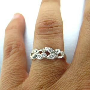 Puede incluir: Un anillo de plata con un delicado dise&ntilde;o de hojas y peque&ntilde;as piedras transparentes.