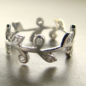 May include: A silver ring with a delicate design of intertwined branches and small clear stones.