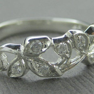 Puede incluir: Un anillo de plata con un dise&ntilde;o delicado que presenta m&uacute;ltiples hojas y peque&ntilde;as piedras transparentes.
