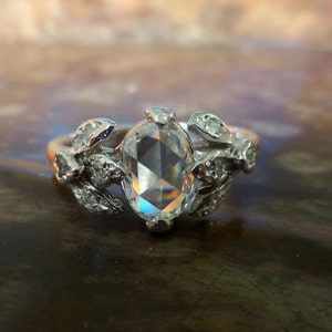 May include: A silver ring with a large, clear, oval-shaped gemstone surrounded by smaller, clear gemstones set in a floral design.