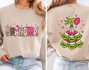Puede incluir: Sudadera beige con la palabra "GRANDMA" en una fuente colorida y festiva en la parte delantera. La parte trasera presenta una mano verde que sostiene seis adornos en forma de corazón verdes y rosas, cada uno con la palabra "Name". Copos de nieve rosas están dispersos alrededor del diseño.