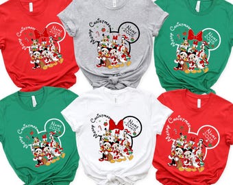 May include: A collection of six t-shirts in red, gray, green, and white. Each shirt features a graphic of Disney characters in a Christmas theme, with the text "Merry Christmas" and "Name 2025" in a Mickey Mouse ear design.