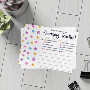 Puede incluir: Una tarjeta blanca con el texto "Amazing Teacher!" y diseños de estrellas coloridas. La tarjeta incluye secciones para rellenar para la personalización. La tarjeta está diseñada para agradecer a un profesor.