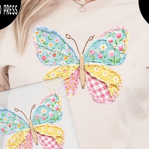 May include: A beige t-shirt featuring a colorful butterfly design. The butterfly has blue, yellow, pink, and red patterned wings. The text "DTF TRANSFER READY TO PRESS" and "HEAT PRESS OR IRON ON" are printed on the image.