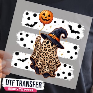 May include: A DTF transfer sheet featuring a ghost with a leopard print pattern wearing a black witch hat. The ghost holds an orange jack-o'-lantern balloon. The background includes three horizontal white brush strokes with black polka dots and bats.