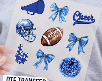 May include: A DTF transfer sheet featuring blue cheerleading and football graphics including a megaphone, three blue bows, the word Cheer, a blue football helmet, a brown football, a number one foam finger, and a blue pom-pom on a clear film.