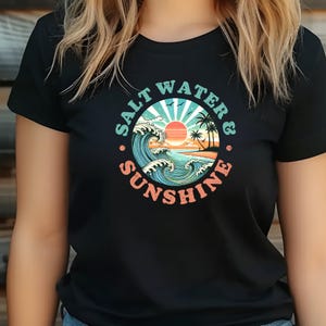 May include: Black t-shirt with a graphic of a sunset over the ocean with waves and palm trees. The graphic is in a circle with the text "Salt Water & Sunshine" around it.